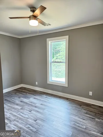 a view of an empty room with window and wooden floor