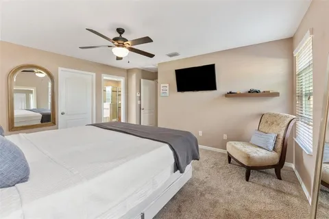 a spacious bedroom with a bed a couch and a flat screen tv
