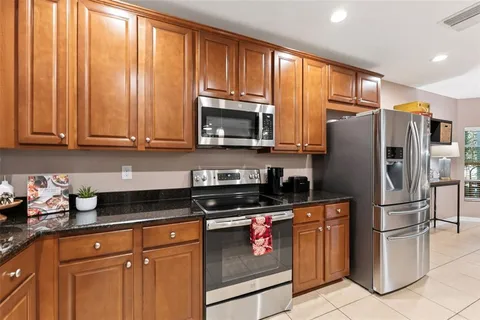 a kitchen with granite countertop a refrigerator stove and microwave