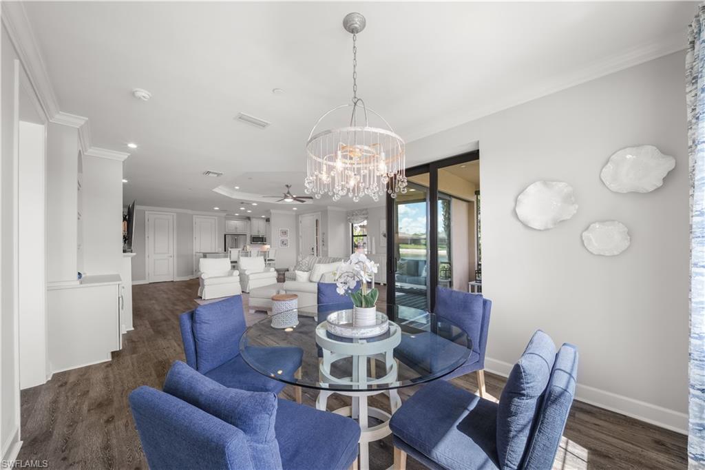 9685 Montelanico Loop, Unit 101 Naples, FL 34119 - Photo 16 of 49 a view of a dining room with furniture a chandelier and wooden floor