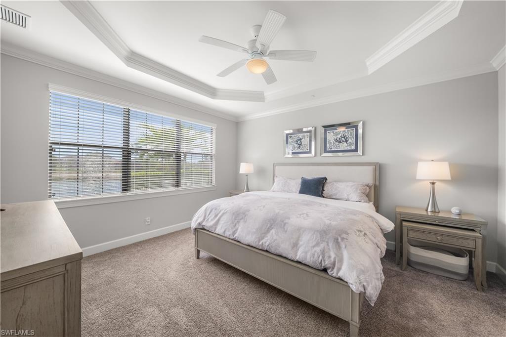 9685 Montelanico Loop, Unit 101 Naples, FL 34119 - Photo 18 of 49 a spacious bedroom with a large bed and a chandelier