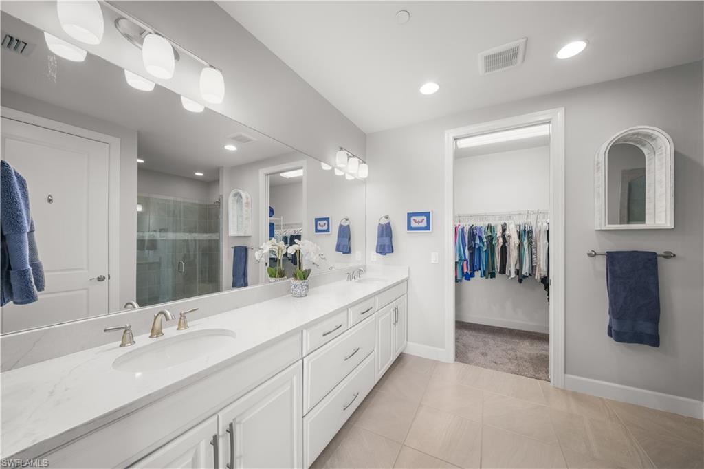 9685 Montelanico Loop, Unit 101 Naples, FL 34119 - Photo 20 of 49 a spacious bathroom with a double vanity sink shower and a mirror