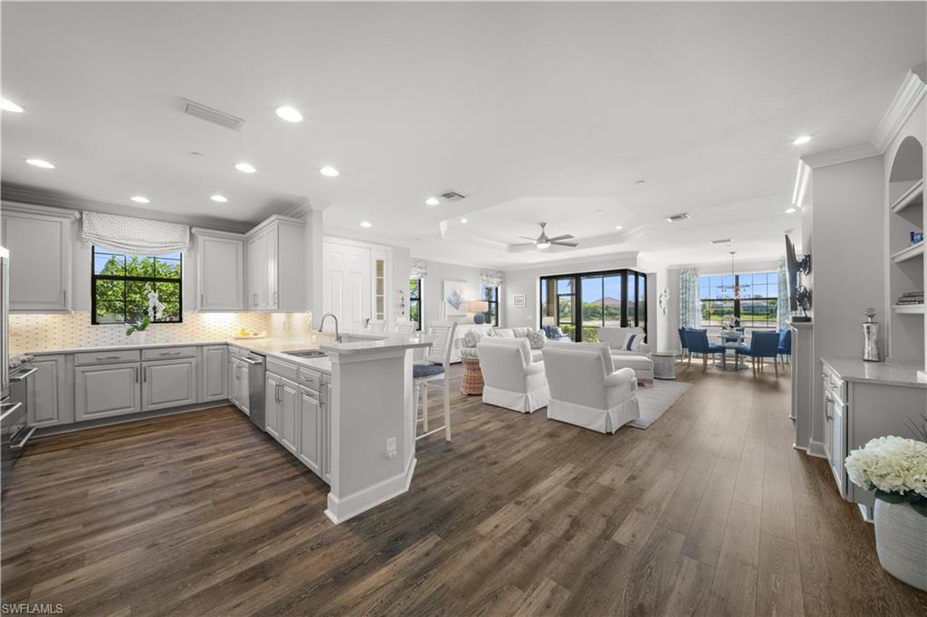 9685 Montelanico Loop, Unit 101 Naples, FL 34119 - Photo 6 of 49 a large white kitchen with wooden floors and white stainless steel appliances