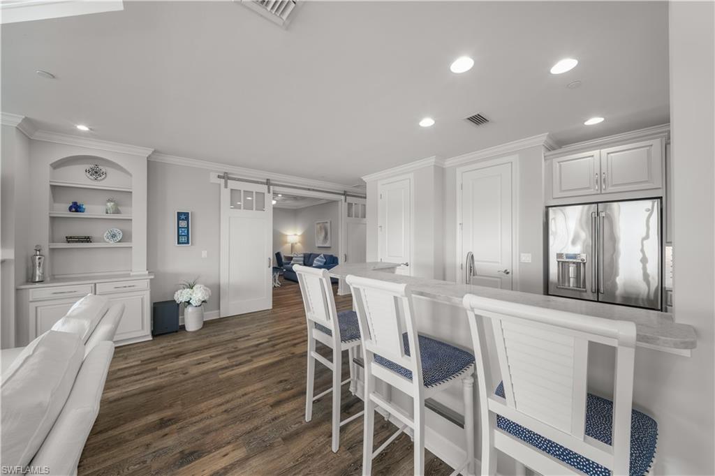 9685 Montelanico Loop, Unit 101 Naples, FL 34119 - Photo 7 of 49 a kitchen with stainless steel appliances kitchen island granite countertop a refrigerator a sink dishwasher and white cabinets with wooden floor