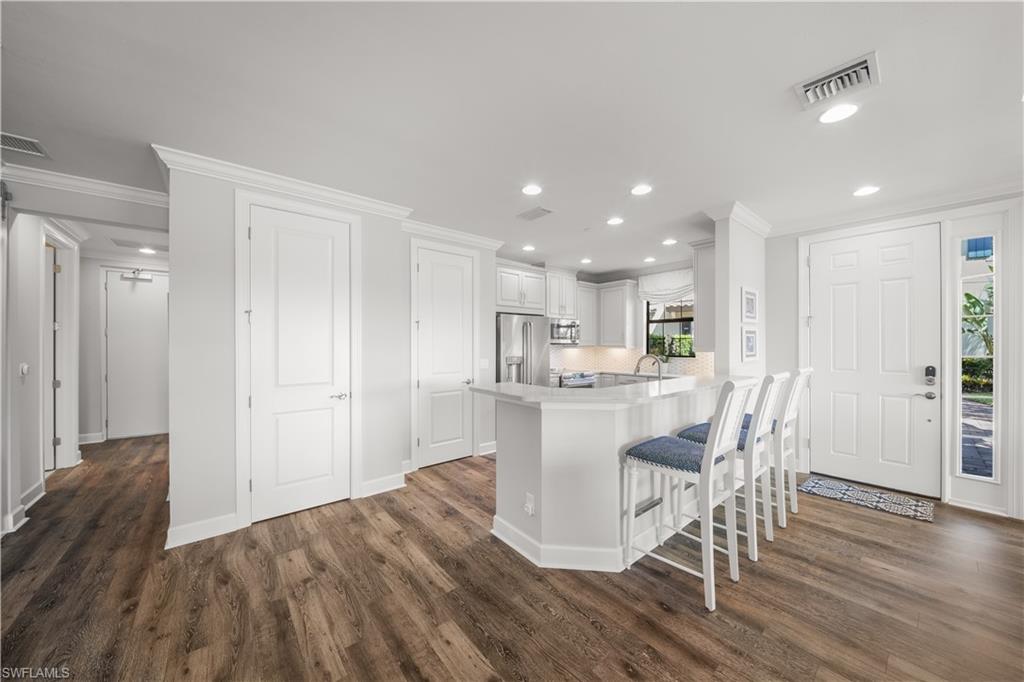 9685 Montelanico Loop, Unit 101 Naples, FL 34119 - Photo 8 of 49 a kitchen with kitchen island wooden floors appliances and cabinets