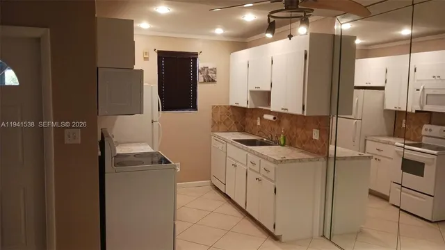 a kitchen that has a sink a refrigerator and a stove top oven