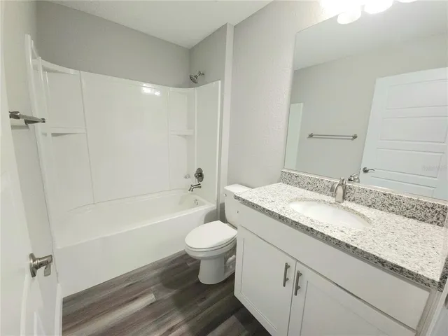 a bathroom with a granite countertop toilet a sink and a bathtub