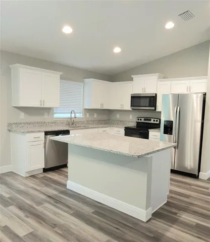 a kitchen with kitchen island granite countertop white cabinets and refrigerator