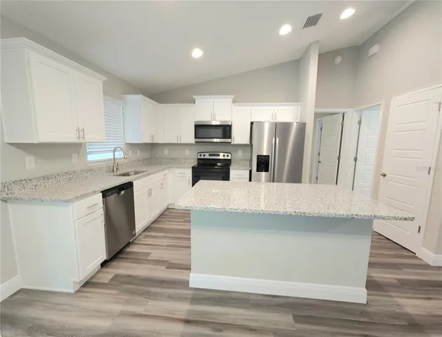 a kitchen with stainless steel appliances kitchen island granite countertop a refrigerator and a stove top oven