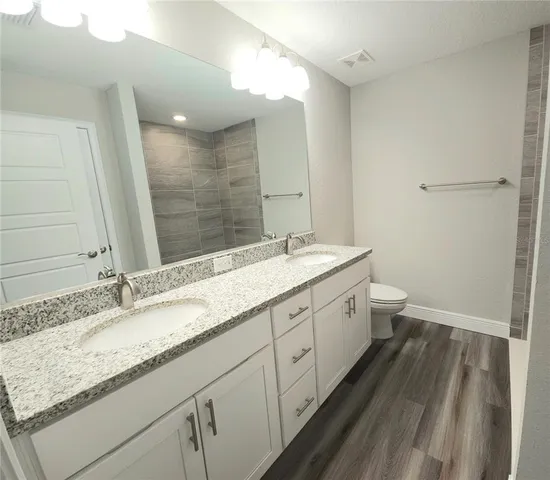 a bathroom with a granite countertop double vanity sink and mirror