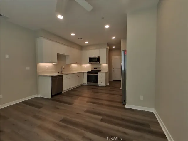 a open kitchen with a sink and dishwasher a refrigerator with wooden floor