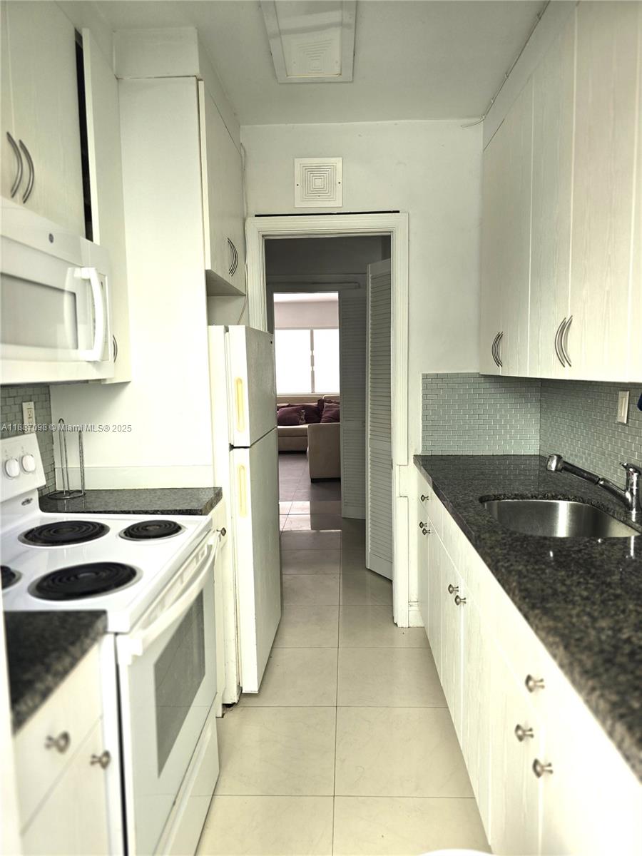 835 Meridian Avenue, Unit 4 Miami Beach, FL 33139 - Photo 10 of 12 a kitchen with granite countertop a sink stove and cabinets