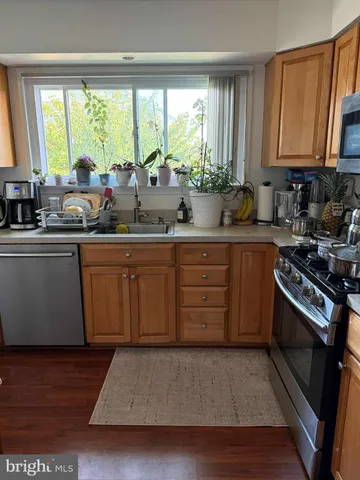 a kitchen with stainless steel appliances granite countertop wooden cabinets a stove a sink and a large window