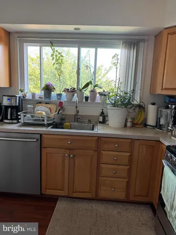 a kitchen with stainless steel appliances wooden cabinets a sink and a large window