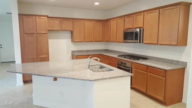 a kitchen with stainless steel appliances granite countertop a sink a stove and a microwave with cabinets