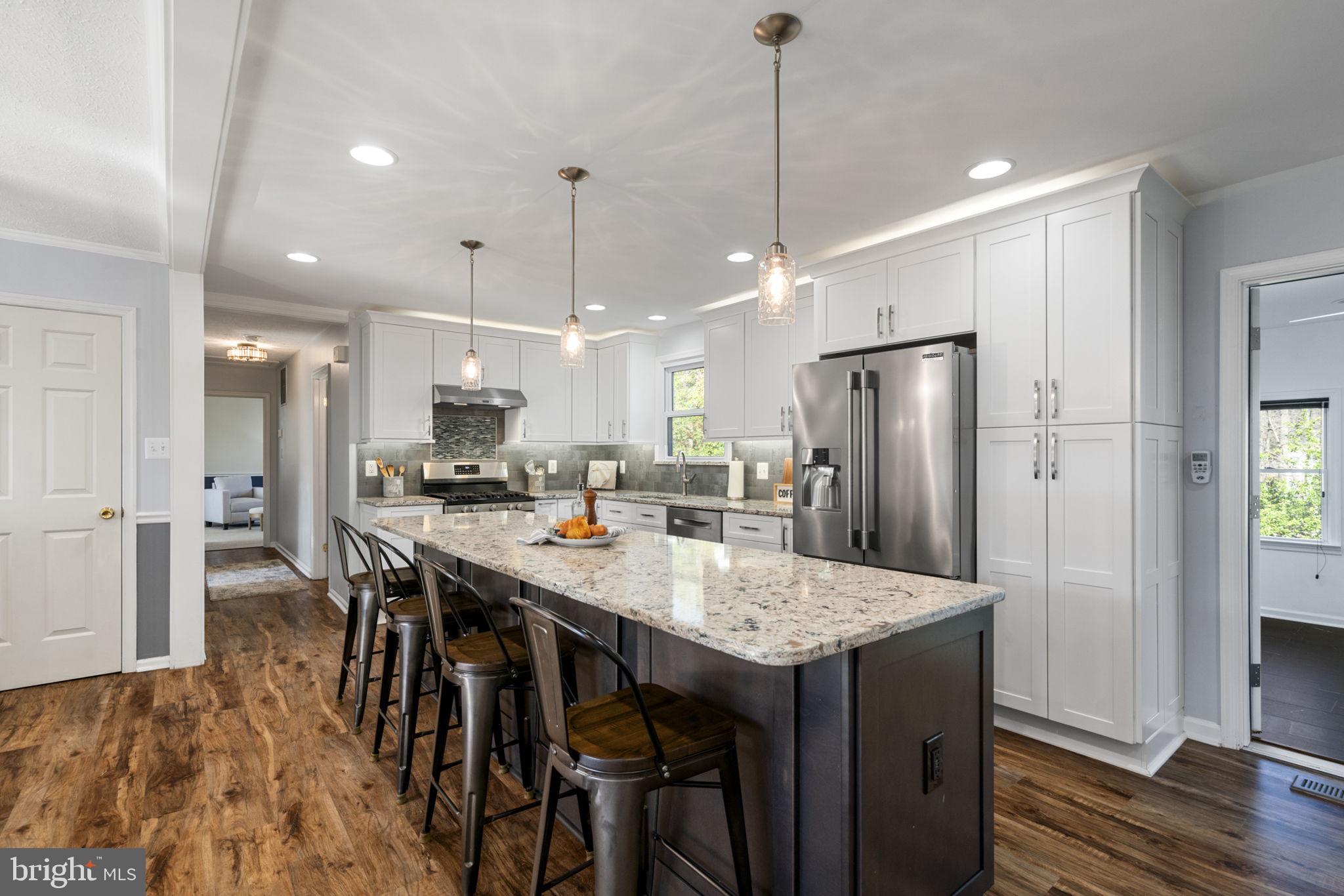 18607 Cabin Road Triangle, VA 22172 - Photo 11 of 64 a kitchen with stainless steel appliances kitchen island wooden floor and refrigerator