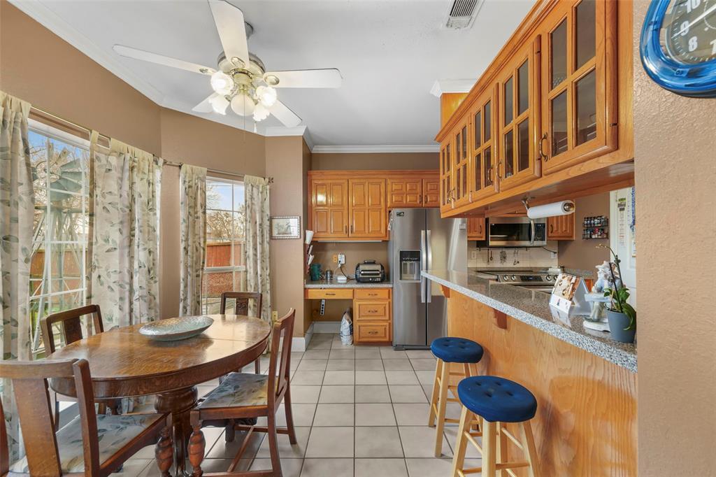 301 Elm Street Quinlan, TX 75474 - Photo 10 of 40 a kitchen with stainless steel appliances granite countertop a stove a refrigerator a oven a dining table and chairs with wooden floor