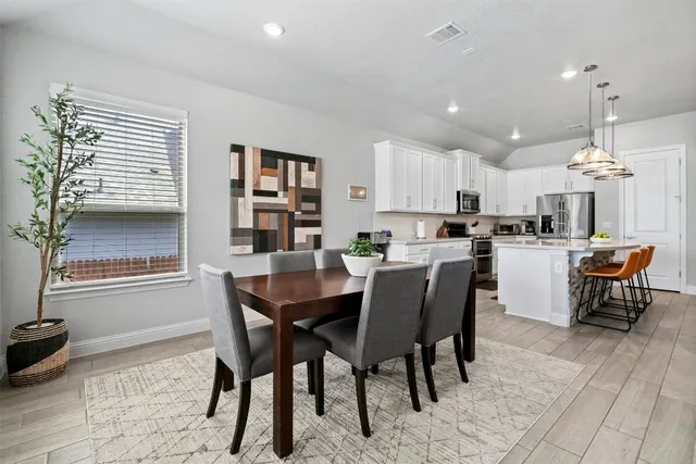 a kitchen with a dining table chairs and refrigerator