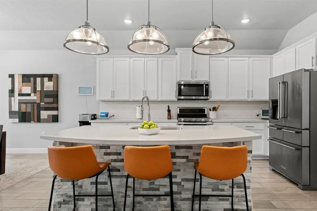 a kitchen with stainless steel appliances granite countertop a dining table chairs and a refrigerator