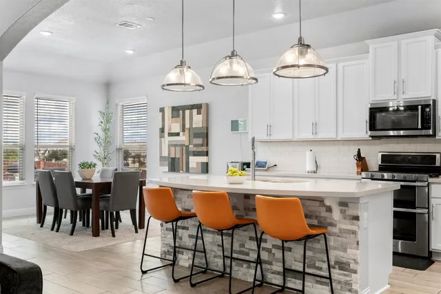 a kitchen with stainless steel appliances a dining table chairs and white cabinets