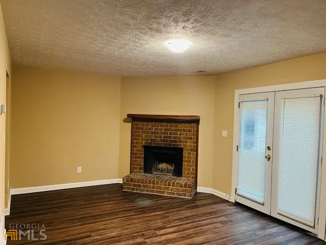 a view of an empty room with wooden floor and a fireplace
