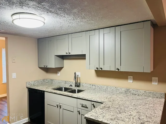 a kitchen with granite countertop a sink a stove and cabinets
