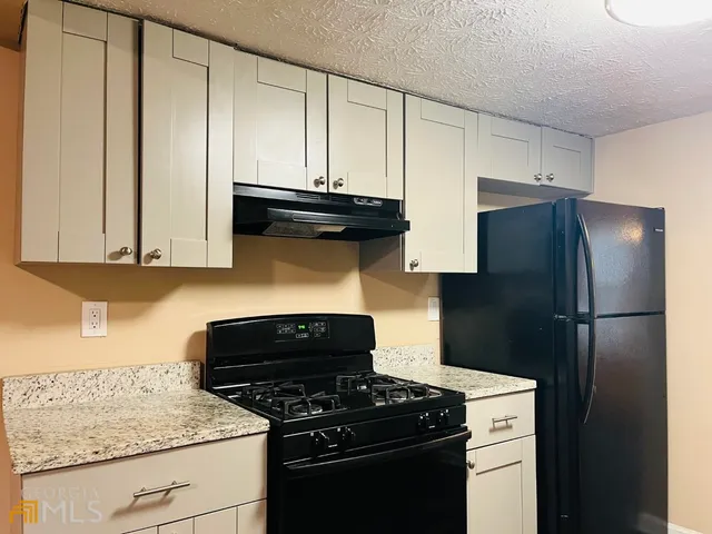 a kitchen with stainless steel appliances granite countertop a refrigerator stove and cabinets