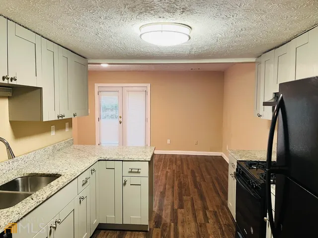 a kitchen with granite countertop a refrigerator and a sink