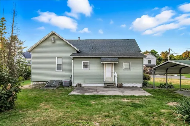 a view of a yard in front of a house with plants and large tree