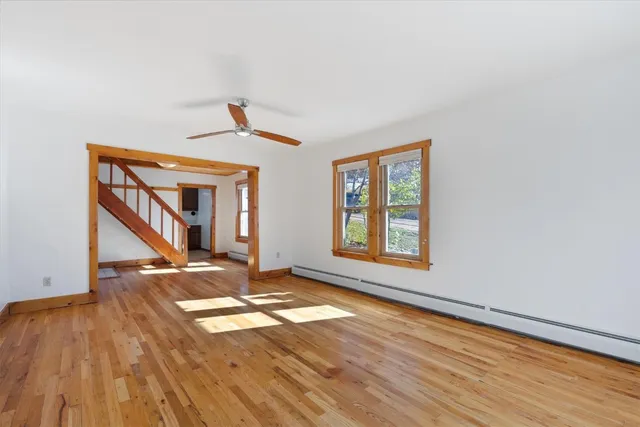 a view of an empty room with wooden floor and a window