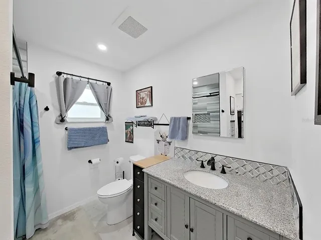 a bathroom with a granite countertop toilet sink and mirror
