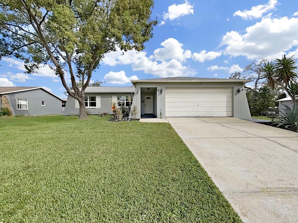 8527 Jolly Roger Drive Hudson, FL 34667 - Photo 30 of 39 a front view of a house with a garden and trees