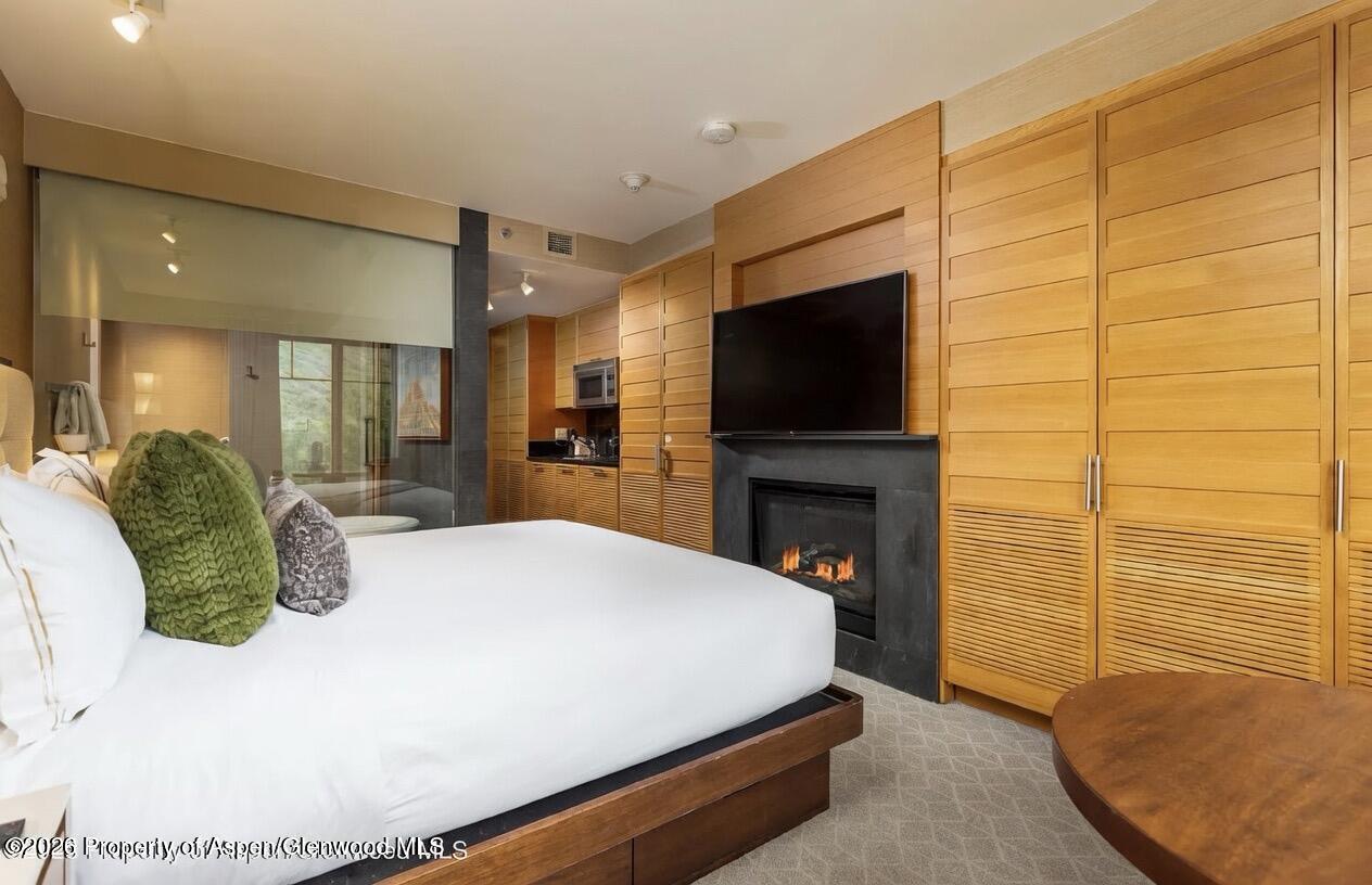 130 Wood Road, Unit 504 Snowmass Village, CO 81615 - Photo 4 of 20 a bedroom with a bed a fireplace and television