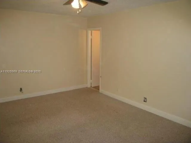 an empty room with a chandelier fan and windows