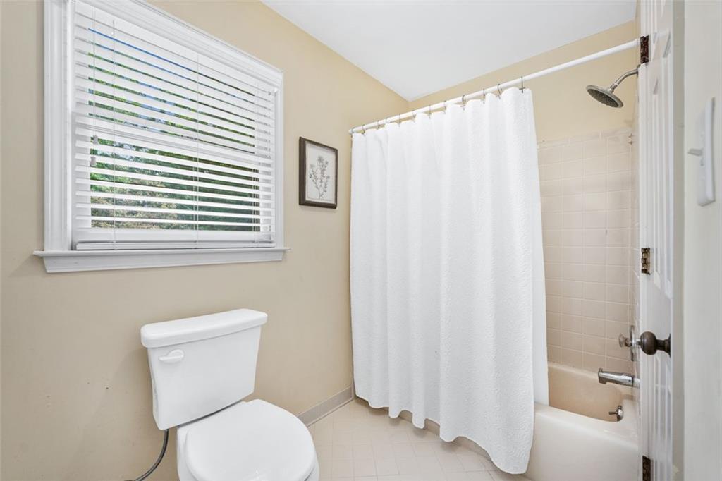 2065 Innsfail Drive Snellville, GA 30078 - Photo 34 of 71 a white toilet sitting next to a bathroom sink and a shower curtain