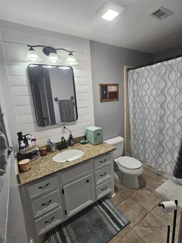 a bathroom with a granite countertop toilet sink and mirror