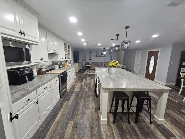 a kitchen with stainless steel appliances a dining table chairs stove refrigerator and microwave