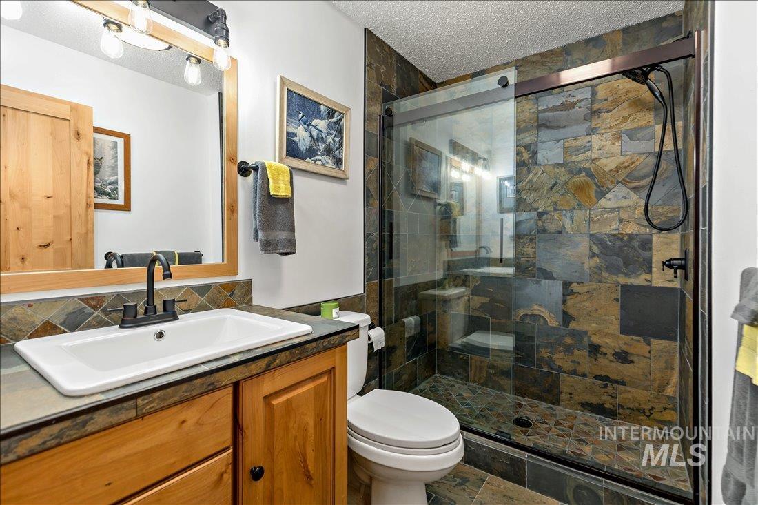 79 Sunset Loop Cascade, ID 83611 - Photo 26 of 44 Walk-in shower with natural stone tile surround and glass enclosure