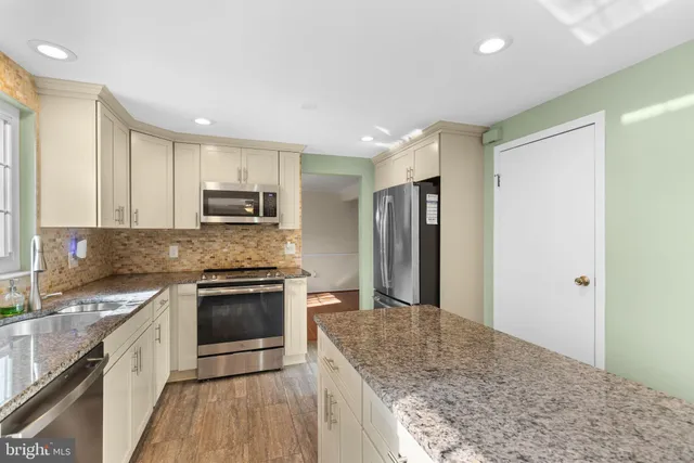 a kitchen with stainless steel appliances granite countertop a stove a sink and a refrigerator