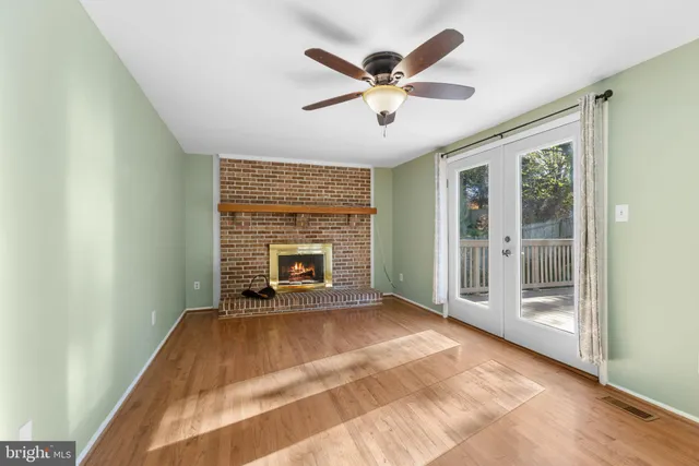 a view of a livingroom with a fireplace a ceiling fan and front door