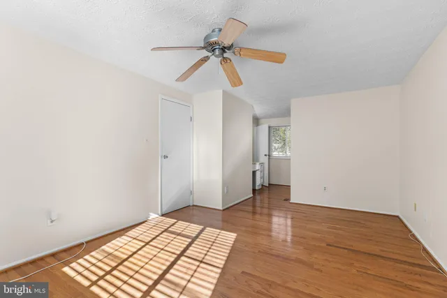 a view of a room with wooden floor and ceiling fan