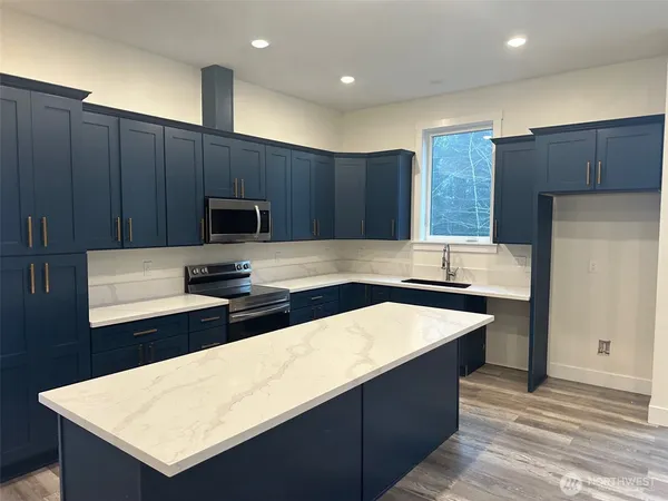 a kitchen with kitchen island granite countertop wooden cabinets a refrigerator and a sink