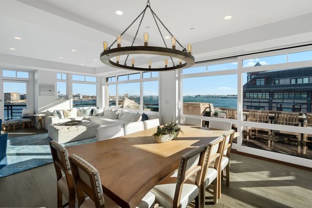 a dining room with stainless steel appliances granite countertop a table chairs and a living room view
