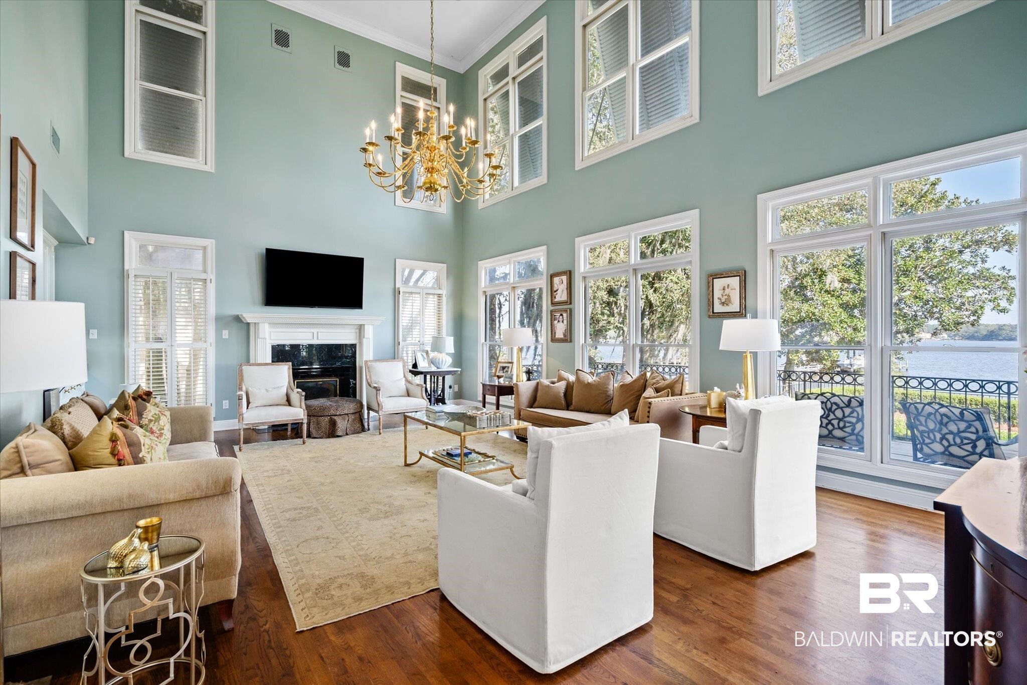 4930 River Trace Theodore, AL 36582 - Photo 5 of 57 Living room featuring a high ceiling, ornamental molding, an inviting chandelier, a fireplace, and dark hardwood / wood-style flooring