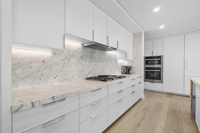 a kitchen with granite countertop white cabinets and stainless steel appliances