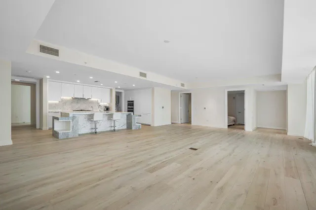 a view of a kitchen with kitchen island a sink wooden floor and a refrigerator