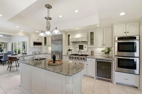 a kitchen with stainless steel appliances granite countertop a stove top oven a sink dishwasher a dining table and chairs