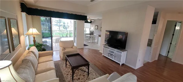a living room with furniture a flat screen tv and a floor to ceiling window