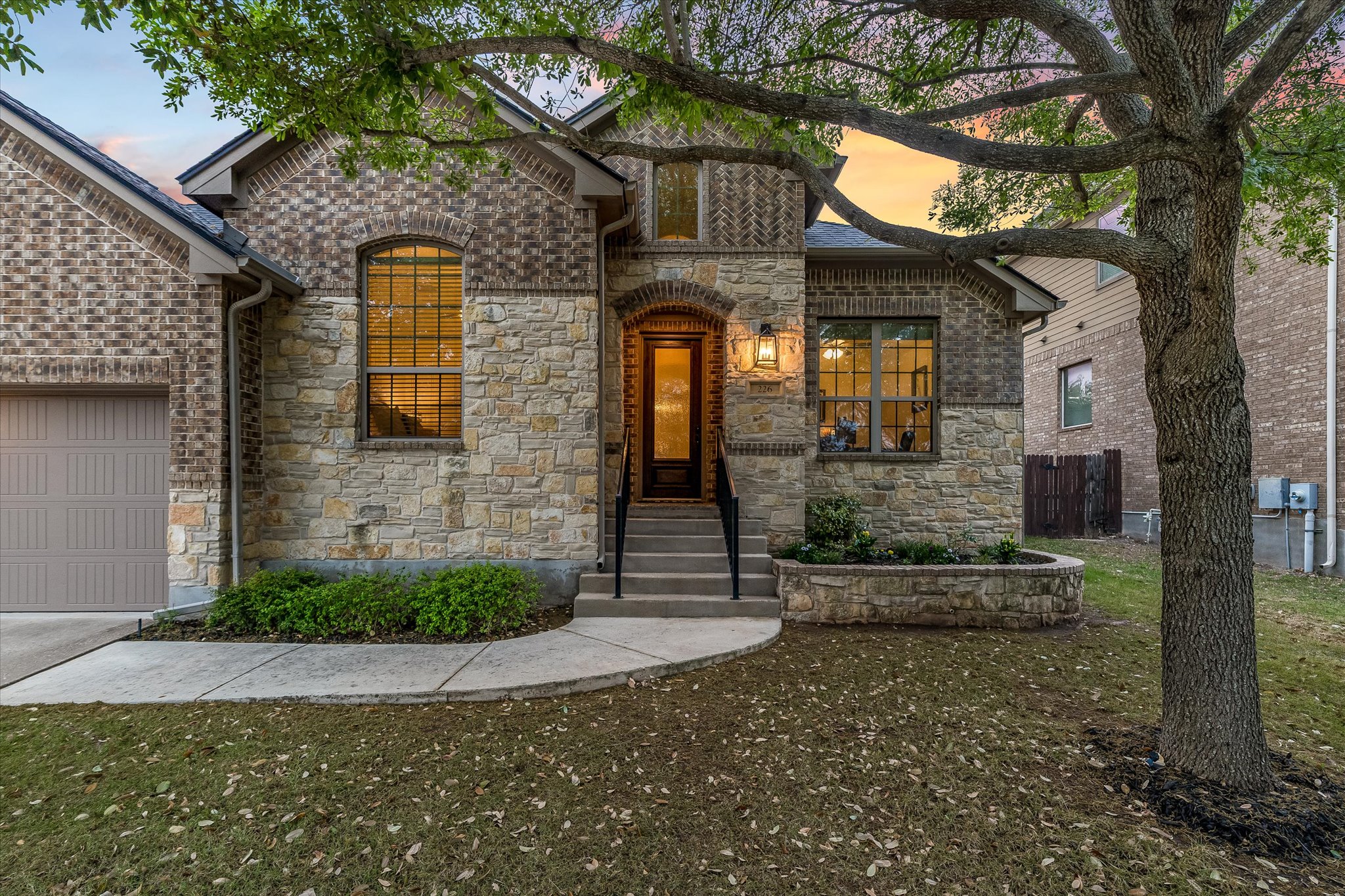 226 Galloway Lane Austin, TX 78737 - Photo 3 of 30 French country style house featuring stone siding, a garage, brick siding, driveway, and a front yard
