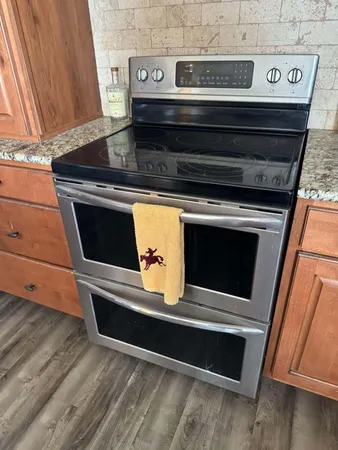 a view of a kitchen with stainless steel appliances granite countertop a sink and a stove